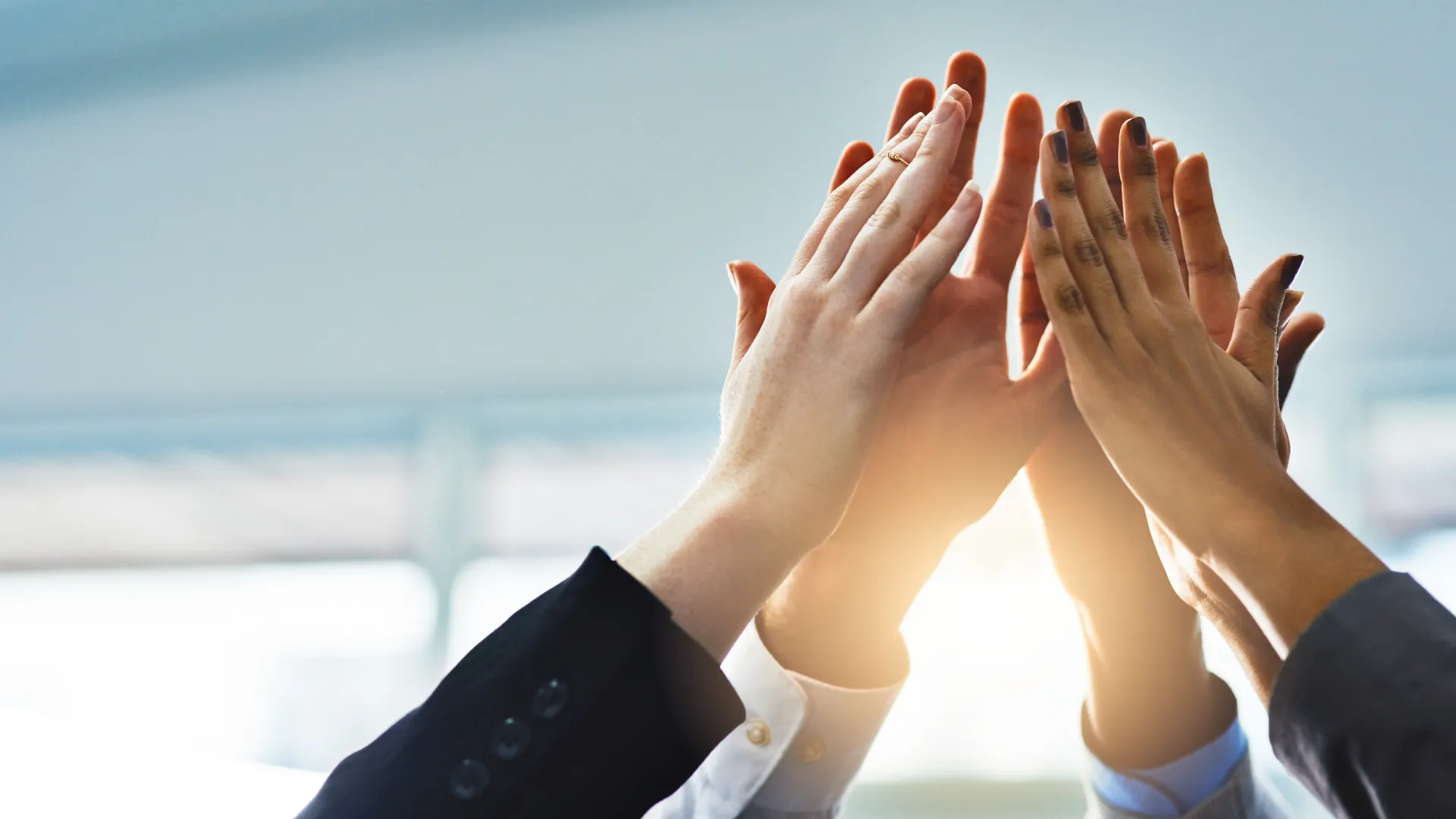Hands high-fiving in a group to symbolize teamwork